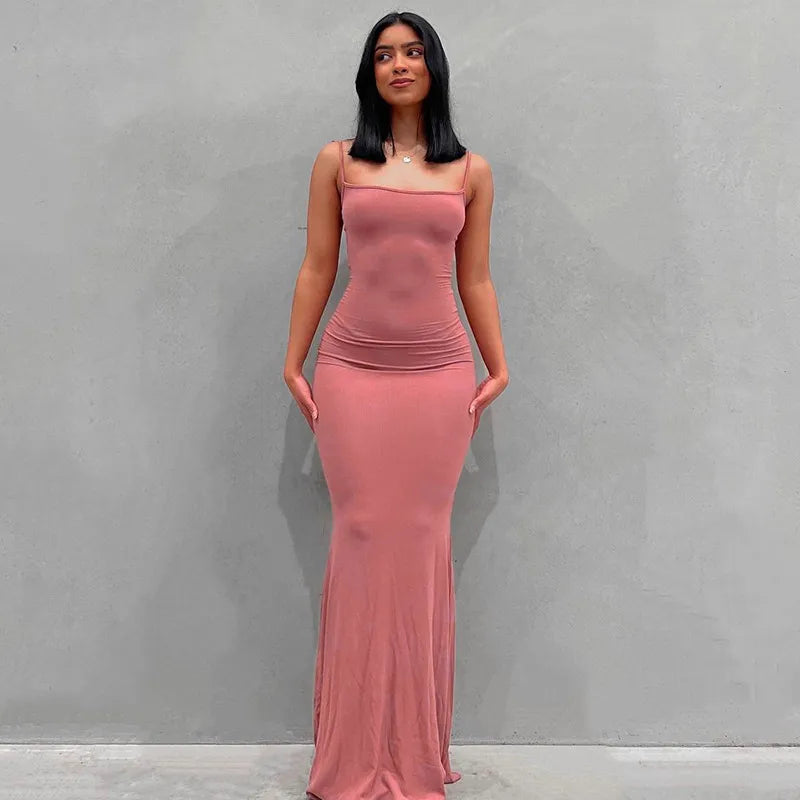 a woman in a pink dress standing in front of a wall